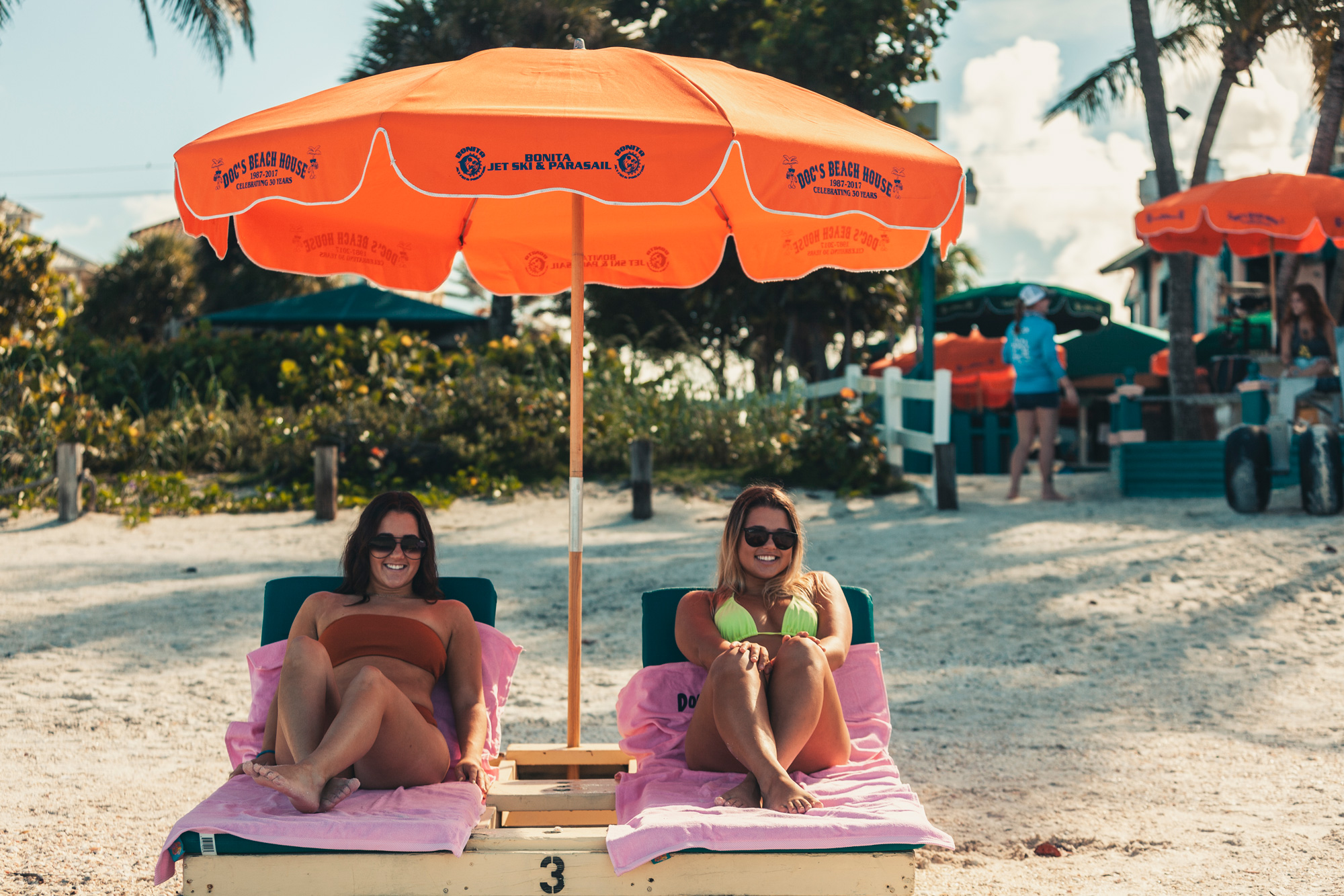 Two girls smiling at the camera while lounging on the beach