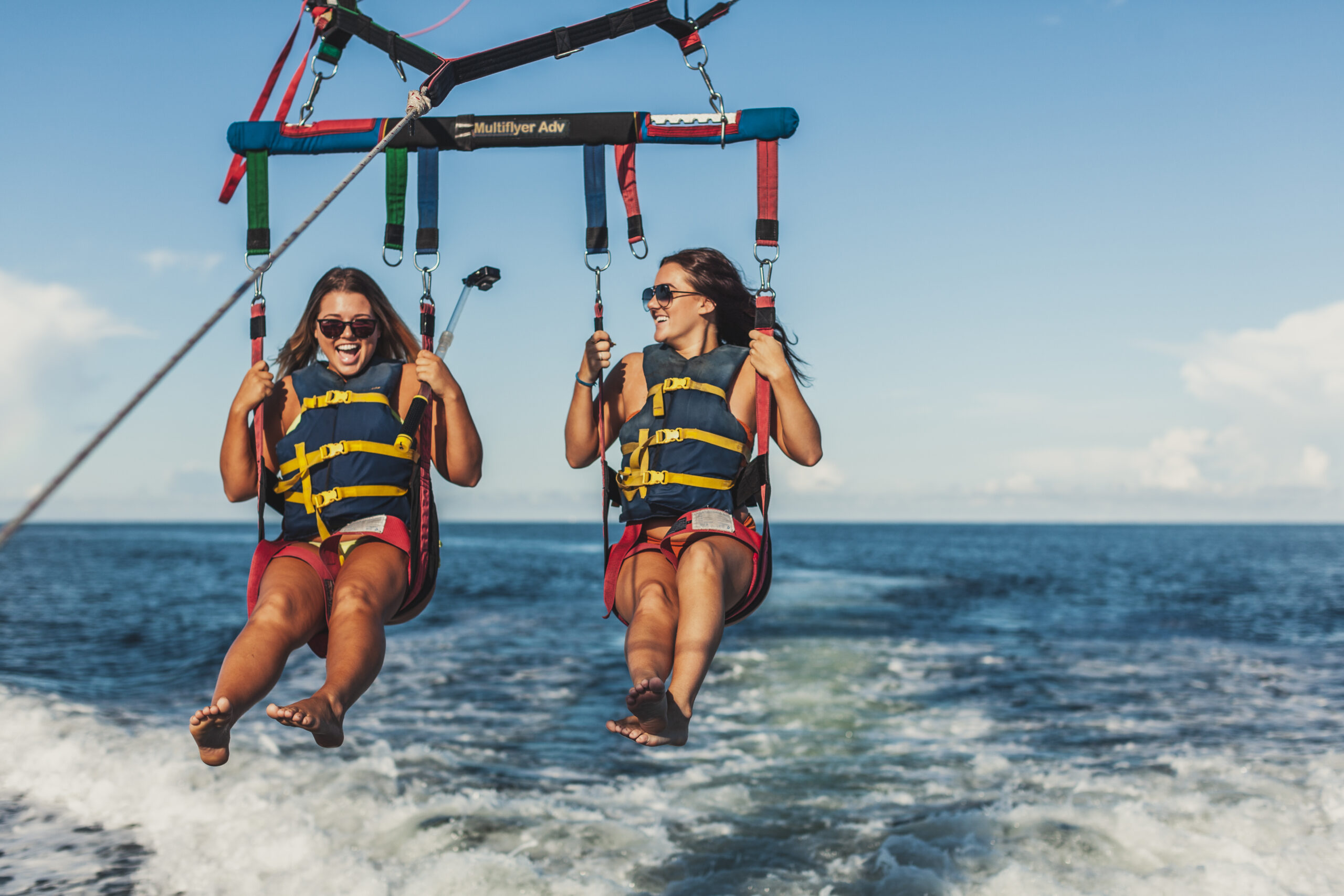 Two girls laughing and smiling while parasailing