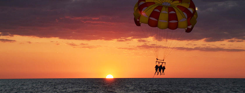 3 parasailers silhouetted in the sunset